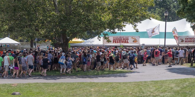Thousands of visitors to the Michigan Brewers Guild 2019 Summer Beer Festival make their way to the entry gates at the start of Saturday's session in Ypsilanti's Riverside Park.