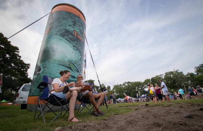 Keturah Godfrey and Bruce Wood, of Taylor, sit in the shadow of a giant inflatable Bell's Two Hearted Ale can while tasting beer samples and studying a list of the 150 breweries and 1,100-plus beers at the Michigan Brewers Guild Summer Beer Festival in Riverside Park in Ypsilanti Friday.