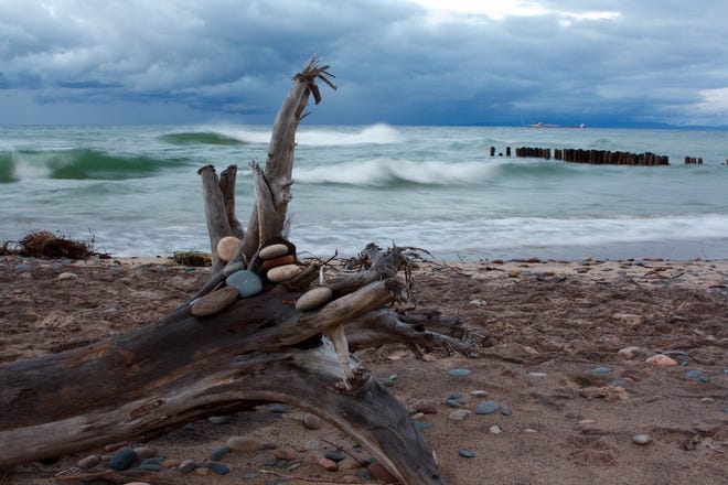 " Stormy Fall, Lake Superior, " by Devon Kotke of Williamston. This photo was taken on a fall visit to Whitefish Point, one of his favorite spots in Michigan. " I ' m not sure who placed the rocks on the driftwood, nor am I sure of what freighter that is, but I love how they add to the photo, " he said. " I think this photo captures the essence of Michigan, particularly the ruggedness and beauty of Lake Superior.