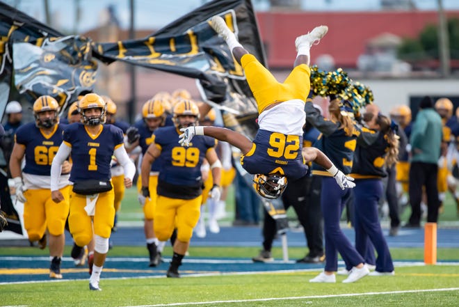 Fordson ' s KeyShawn Smith (26) leads his team onto the field and does a flip before Friday ' s game against Belleville.