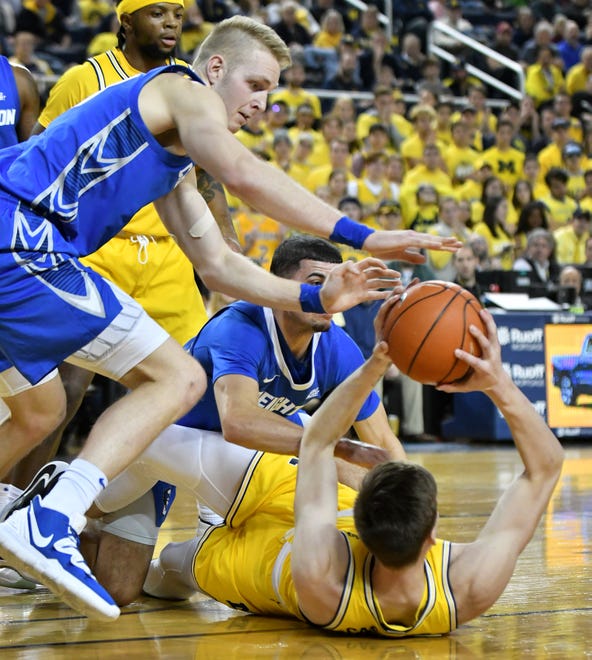 Michigan forward Colin Castleton, bottom, tries to pass the ball away from Creighton's Kelvin Jones, left, and Marcus Zegarowski in the second half.