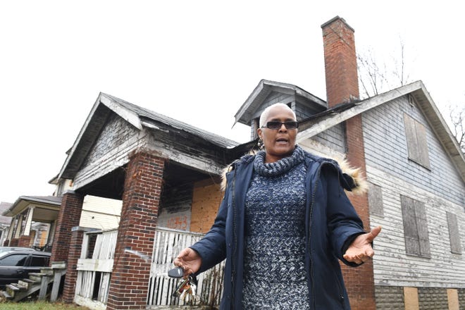 Jackie Smith of Detroit is concerned about the vacant boarded up house (background) next to her home in Detroit and has been trying to get it demolished and cleared away.