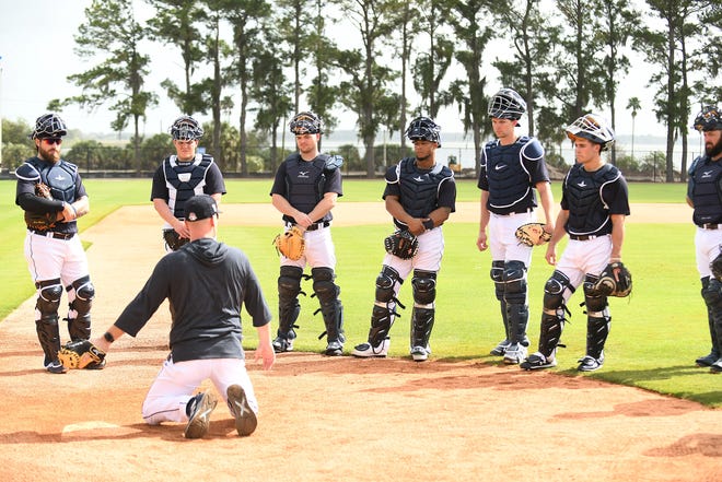 Catchers listen to quality control coach Josh Paul talk about covering home.
