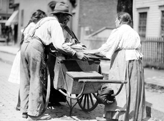 A fish peddler sells his wares on a Detroit street circa 1910.