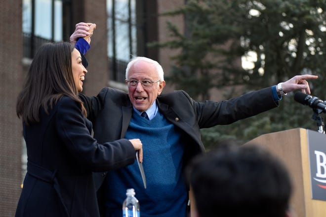 U.S. Senator and presidential candidate Bernie Sanders, right, is introduced to the crowd by U.S. Representative Alexandria Ocasio-Cortez on the campus of The University of Michigan, Sunday, March 8, 2020.