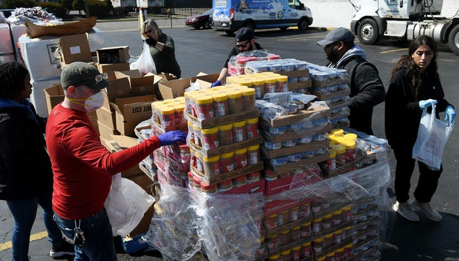 From left, Gleaners' Sydni Davis, 26, of Southfield, Tim Crandall, 39, of Detroit, Annette Hoyer of Westland, Steven Stoddard, 28, of Berkley, Omari Taylor of Farmington Hills and Maya Hammoud, 22, of Dearborn load food into bags to be handed out.  Gleaners Community Food Bank operates a drive thru and walk up food drive in Southwest Detroit near the Clemente Recreation Center in Detroit on Mar. 25, 2020.  Gleaners had an entire semi trailer of food which would cover approximately 600 households or families.
