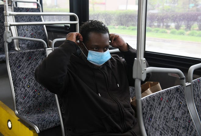 Raymoan Autrey, 48, of Detroit puts on the mask given to him by the bus driver before he got on the 17 bus in Detroit on May 18, 2020. To protect the health and safety of our customers and employees, DDOT is temporarily suspending fare collection for all trips and requesting that customers limit non-essential bus travel until further notice.