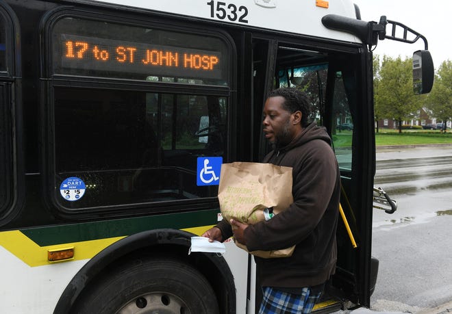 Raymoan Autrey, 48, of Detroit takes the mask given to him by the bus driver before he enters the 17 bus in Detroit on May 18, 2020. To protect the health and safety of our customers and employees, DDOT is temporarily suspending fare collection for all trips and requesting that customers limit non-essential bus travel until further notice.