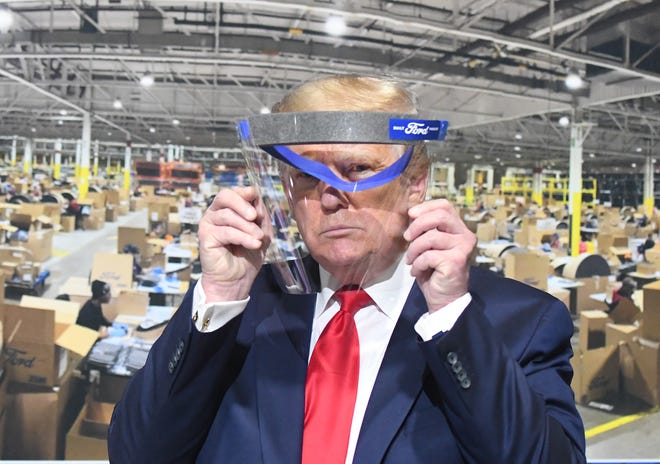 President Trump looks through a face shield, in front of poster of the manufacturing of these shields, while touring Ford Motor Co.'s Rawsonville Components Plant  in Ypsilanti, Michigan on May 21, 2020.