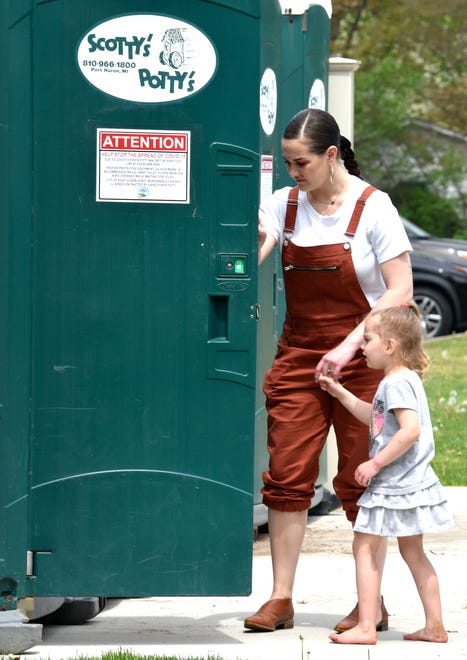 Sydney Vlaminck opens the door for her daughter, Isla, 4, both of Port Huron, as they use the porta-potties.