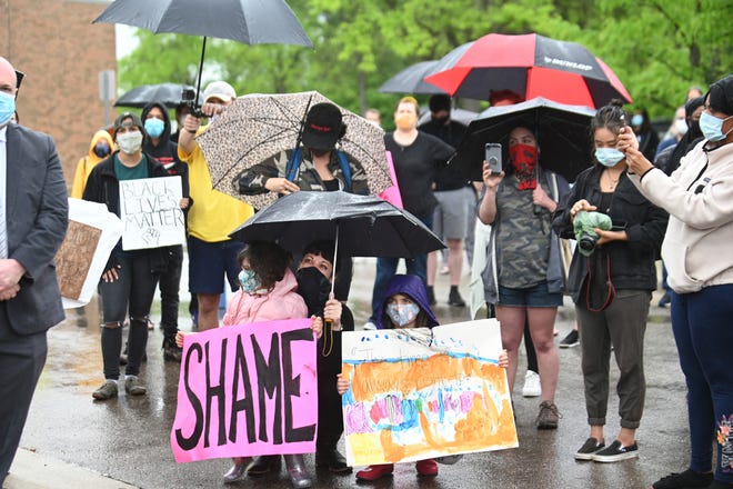 Allison Ivey holds an umbrella with her two daughters, Ramona Ivey and Eleanor Ivey, as they demand justice for Sha'Teina Grady El who was punched repeatedly by a Washtenaw County Sheriffs Deputy and over the death of George Floyd who died in police custody outside the Washtenaw County Sherriff office in Ann Arbor on Friday, May 29, 2020.