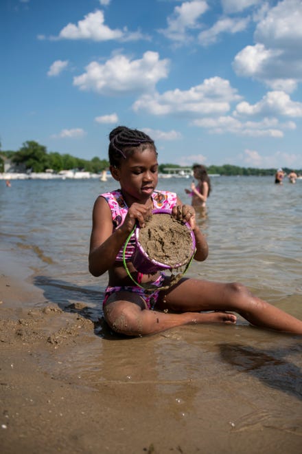 Six-year-old Mia Simmons, of Detroit, builds a sandcastle during a day of warm weather at Mercer Beach, in Walled Lake, June 30, 2020.