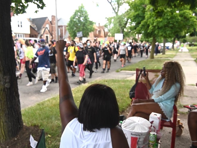 Carolyn Howell of Detroit raises her fist In unity as marchers pass her residence along San Juan Drive in Detroit on Saturday, July 11, 2020.