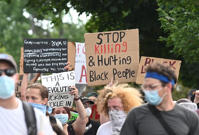 Protesters hold up signs and march along San Juan Drive in Detroit on Saturday, July 11, 2020.
