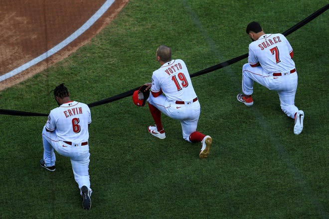 From left to right, Cincinnati Reds' Phillip Ervin, Joey Votto and Eugenio Suarez take a knee prior to a baseball game against the Detroit Tigers at Great American Ballpark in Cincinnati, Friday, July 24, 2020.