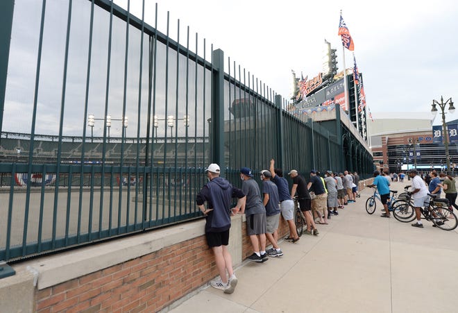 Fans watch the Tigers home opener from outside the centerfield fence.
