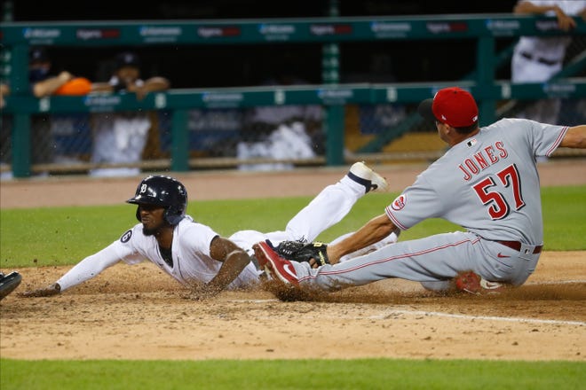 Detroit Tigers' Travis Demeritte beats the tag of Cincinnati Reds relief pitcher Nate Jones (57) to score at home plate on a wild pitch in the seventh inning of a baseball game in Detroit, Friday, July 31, 2020. (AP Photo/Paul Sancya)