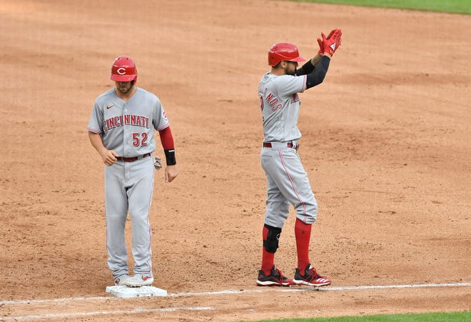 Reds ' Kyle Farmer (52) goes back to first base as Nicholas Castellanos applauds after Tigers right fielder Travis Demeritte (not shown) caught his line drive in the sixth inning.