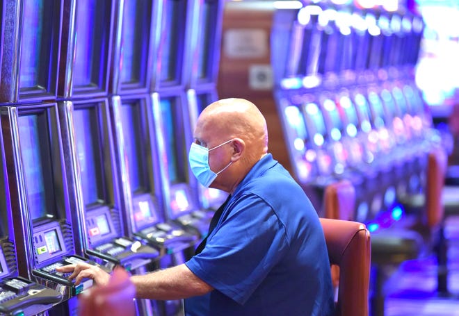 Patron Andrew Donaldson of Detroit wears a mask as he plays the penny slots Wednesday at the MGM Grand Detroit.