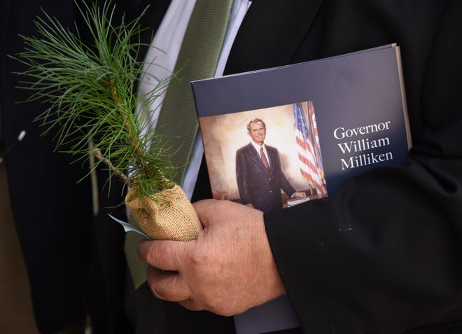 Former Michigan Gov. John Engler holds a memorial program and one of the white pine seedlings which were given out to guests at the end of the memorial for the late Gov. William Milliken.