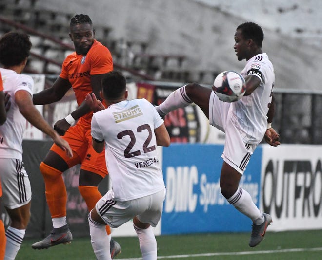 New Amsterdam FC's Isimohi Bello and DCFC's Ibrahim Conteh go after a ball in the first half.