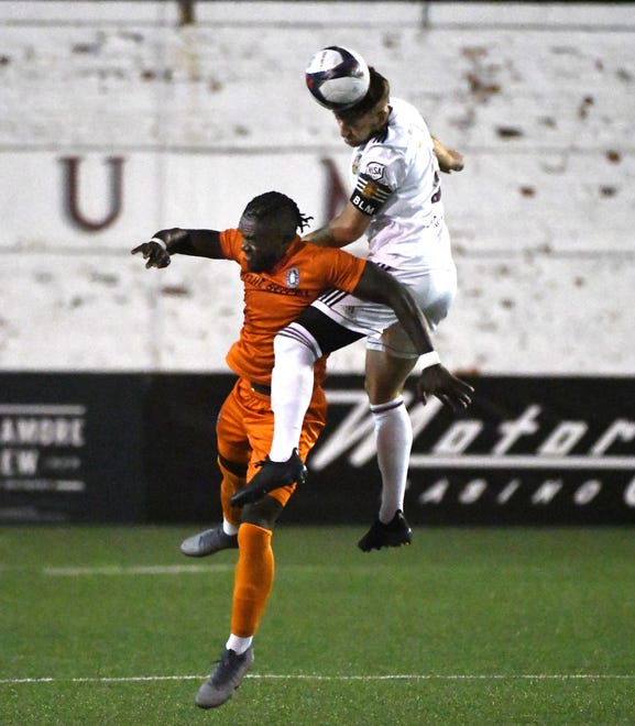 New Amsterdam FC's Isimohi Bello and DCFC's Stephen Carroll go up for a header in the first half.