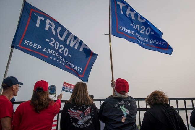 Trump supporters wave flags before the Make America Great Again rally with Donald Trump Jr. and Kid Rock at Bumpers Landing Boat Club in Harrison Township, Mich on Sept. 14, 2020.