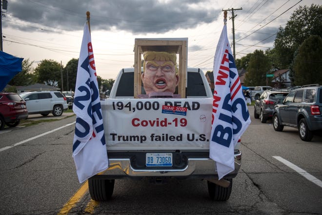 An anti-Trump car drives before the Make America Great Again rally with Donald Trump Jr. and Kid Rock at Bumpers Landing Boat Club in Harrison Township.