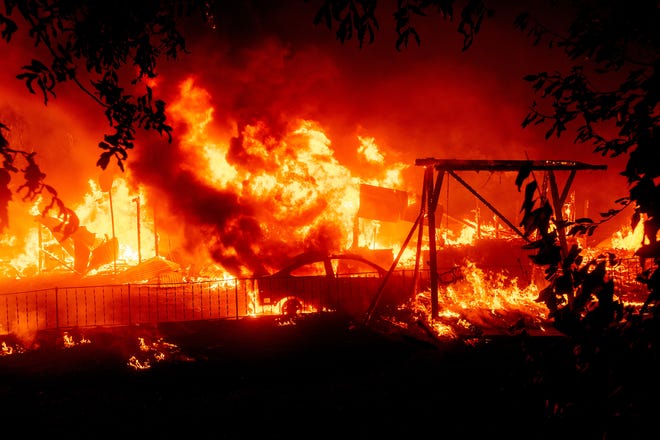 Flames consume a home and car as the Bear Fire burns through the Berry Creek area of Butte County, Calif., on Wednesday, Sept. 9, 2020. The blaze, part of the lightning-sparked North Complex, expanded at a critical rate of spread as winds buffeted the region. (AP Photo/Noah Berger)