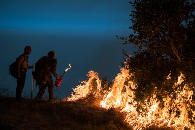 Firefighters light a controlled burn along Nacimiento-Fergusson Road to help contain the Dolan Fire near Big Sur, Calif., Friday, Sept. 11, 2020.