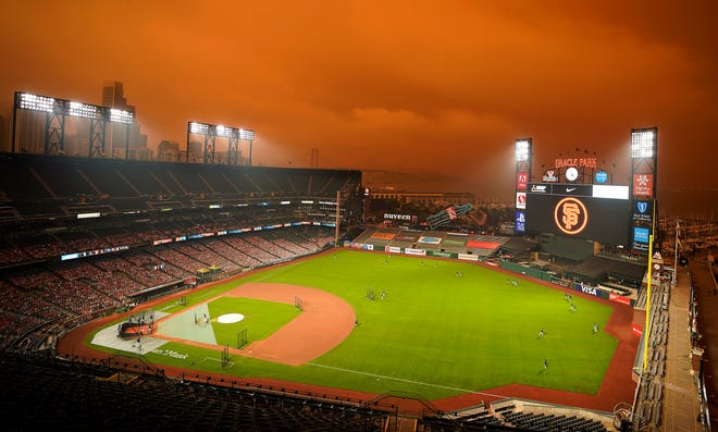 Smoke from California wildfires obscures the sky over Oracle Park as the Seattle Mariners take batting practice before their baseball game against the San Francisco Giants on Wednesday, Sept. 9, 2020, in San Francisco. (AP Photo/Tony Avelar)