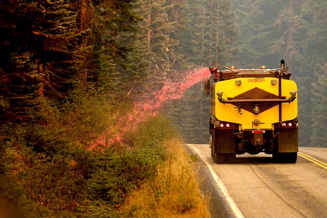 A truck sprays fire retardant on vegetation to help stop the spread of the North Complex Fire in Plumas National Forest, Calif., on Monday, Sept. 14, 2020.