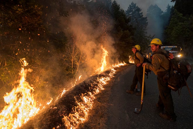 Firefighters monitor a controlled burn along Nacimiento-Fergusson Road to help contain the Dolan Fire near Big Sur, Calif., Friday, Sept. 11, 2020.