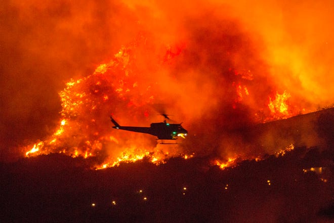 A helicopter prepares to drop water at a wildfire in Yucaipa, Calif., Saturday, Sept. 5, 2020.