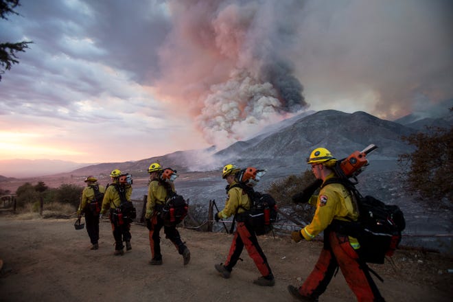 Members of firefighters walk in line during a wildfire in Yucaipa, Calif., Saturday, Sept. 5, 2020. (AP Photo/Ringo H.W. Chiu)