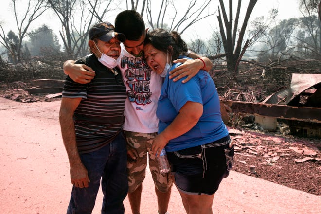 Dora Negrete, right, and her husband Marcelino Rocha, left, and son Hector Rocha console each other after seeing their destroyed mobile home at the Talent Mobile Estates as wild fires devastate the region on Thursday, Sept. 10, 2020 in Talent, Ore.
