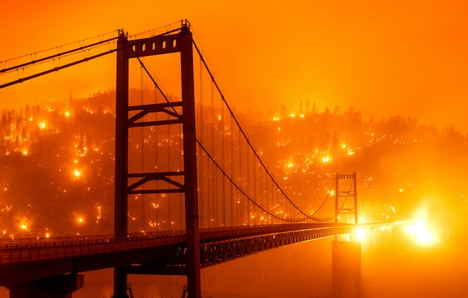 In this image taken with a slow shutter speed, embers light up a hillside behind the Bidwell Bar Bridge as the Bear Fire burns in Oroville, Calif., on Wednesday, Sept. 9, 2020.