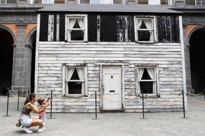 Alice Ridolfi, from Verona, helps her two-year-old son Leone take pictures of the house of U.S. civil rights campaigner Rosa Parks, rebuilt by artist Ryan Mendoza for public display, in Naples, Italy, Tuesday, Sept. 15, 2020. The rundown, paint-chipped Detroit house where Parks took refuge after her famous bus boycott is going on display in a setting that couldn't be more incongruous: the imposing central courtyard of the 18th century Royal Palace. (AP Photo/Gregorio Borgia)