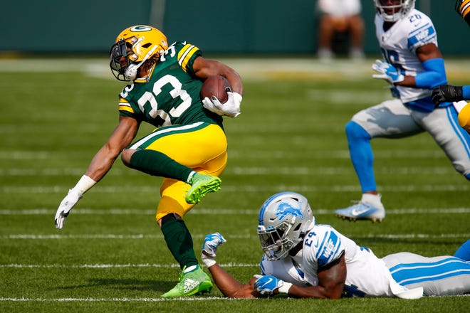 Green Bay Packers' Aaron Jones runs past Detroit Lions' Amani Oruwariye during the first half of an NFL football game Sunday, Sept. 20, 2020, in Green Bay, Wis.