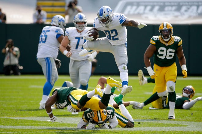 Detroit Lions' D'Andre Swift leaps over Green Bay Packers' Adrian Amos and Raven Greene during the second half of an NFL football game Sunday, Sept. 20, 2020, in Green Bay, Wis.