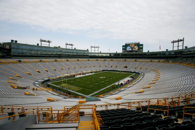 Players begin to warm up as the seats are empty at Lambeau Field before an NFL football game between the Green Bay Packers and the Detroit Lions.