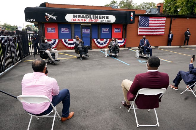 Democratic vice presidential candidate Sen. Kamala Harris, D-Calif., listens as Reverend Wendell Anthony, second from left, speaks at Headliners Barbershop in Detroit, while those in attendance observe social distancing.