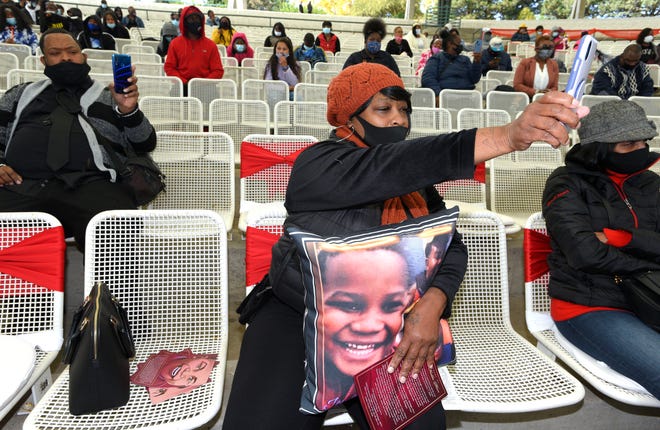 Tai'raz's cousin, Deshon Evans, of Detroit, takes pictures of the event as she holds a pillow with the image of Tai'raz Moore.