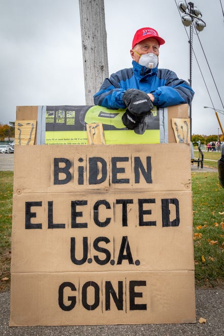 Glenn Kangas, 82, from Cadillac stands with a sign in support of Donald Trump outside the rally. President Donald Trump spoke to supporters at a rally at Muskegon County Airport in Muskegon on Oct. 17, 2020.