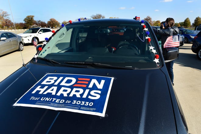 Beverly Hills, Mich. residents Mirjam Gunter, front, and Jessica Damoiseaux decorate their vehicle with various signs to show their support of Democratic presidential candidate former Vice President Joe Biden at a campaign rally, Saturday, Oct. 31, 2020, in Detroit.