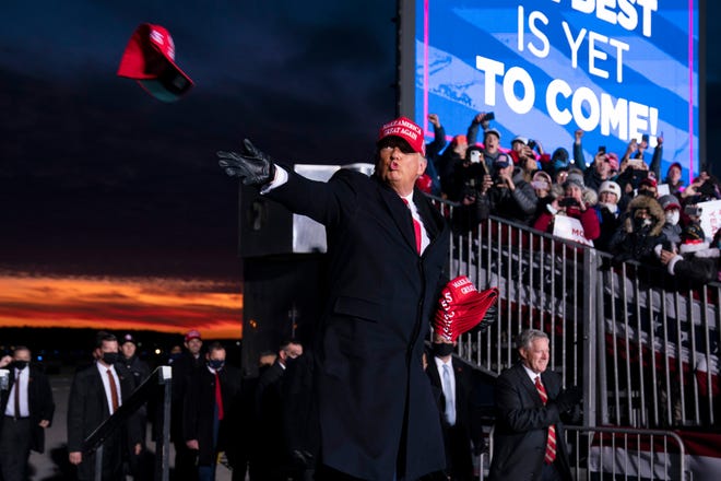 President Donald Trump throws hats to supporters as he arrives for a campaign rally at Cherry Capital Airport, Monday, Nov. 2, 2020, in Traverse City, Mich.