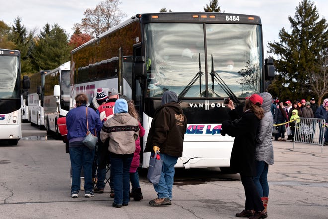 Supporters line up to take shuttle buses to see President Donald Trump at a campaign rally in Traverse City, Mich. Monday, Nov. 2, 2020.