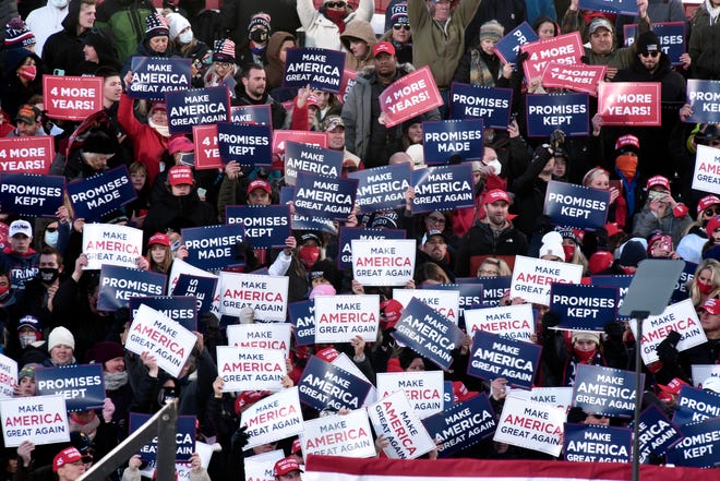 Supporters hold campaign signs as they wait for President Donald Trump at a campaign rally in Traverse City, Mich. Monday, Nov. 2, 2020.