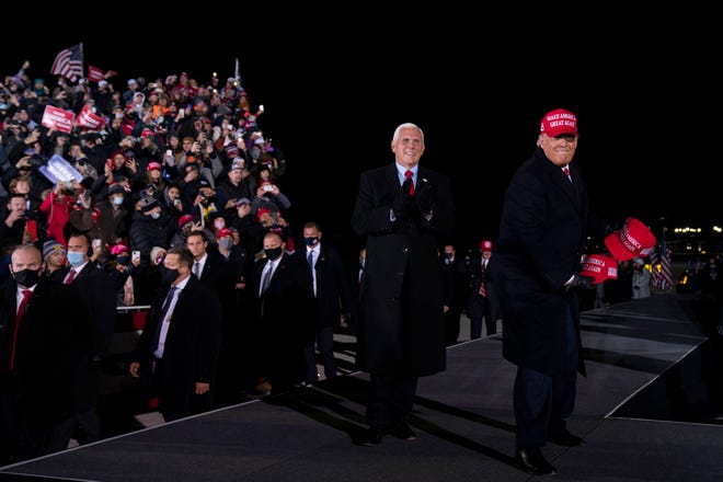 President Donald Trump throws hats to supporters as he and Vice President Mike Pence arrive for a campaign rally at Gerald R. Ford International Airport, Monday, Nov. 2, 2020, in Grand Rapids, Mich.