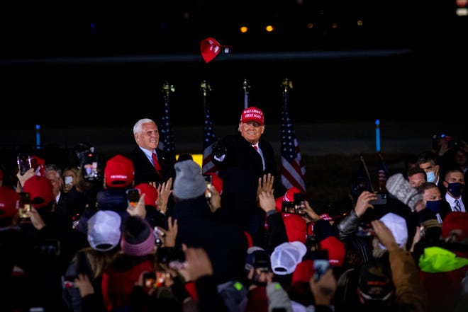 President Donald Trump throws a MAGA hat into the crowd before he delivers remarks at his fifth and final rally of the day—and the campaign—at Gerald R. Ford Airport in Grand Rapids, Michigan on November 2, 2020.  The rally started at midnight and went into election day.